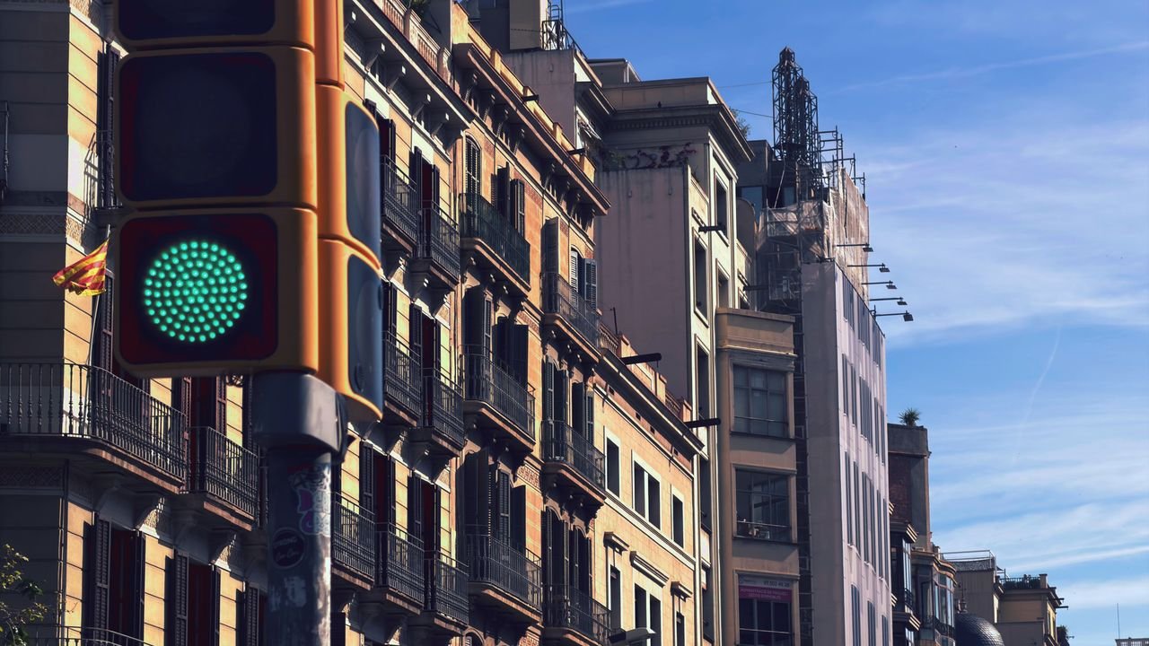 Fully Funded Scholarships in Spain for International Students 2026 and 2027 Daytime urban scene in Barcelona with a green traffic light and historic architecture.